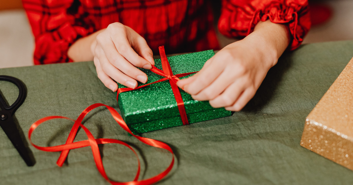 paket wird weihnachtlich eingepackt mit grünem Papier und roter Schleife